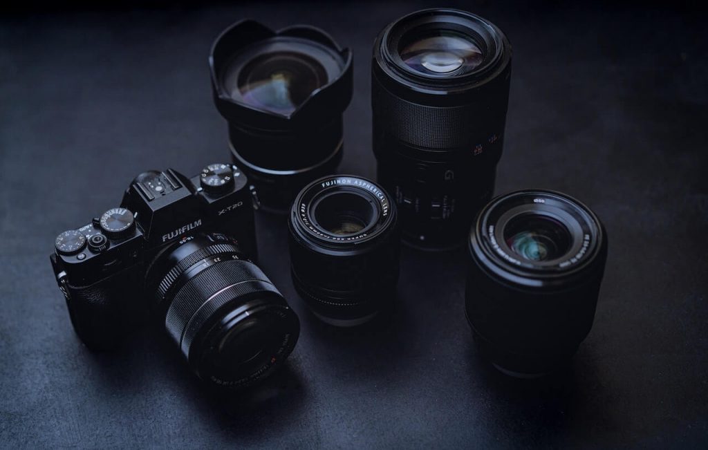 La imagen de una cámara rodeada de una colección de objetivos muestra la versatilidad y el equipamiento de la fotografía.